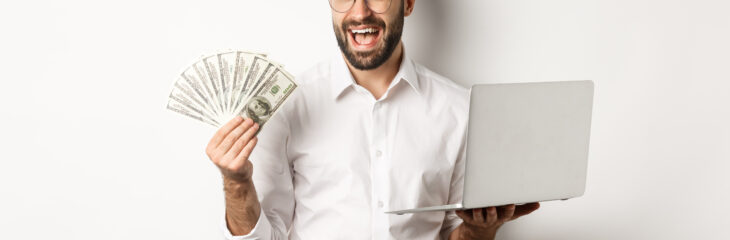 Business and e-commerce. Confident businessman showing how work online, winking, holding money and laptop, standing over white background